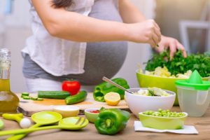 Mujer embarazada cocinando saludable