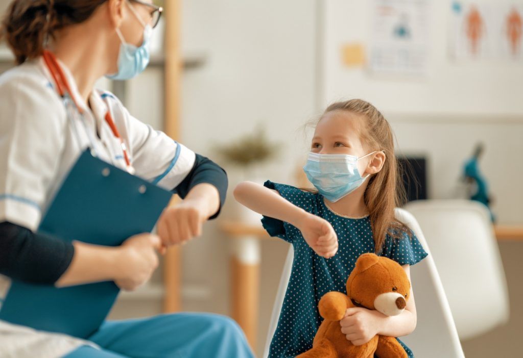 Pediatra saludando a niña con el codo